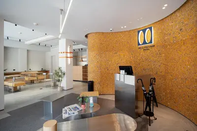 a lobby with a wall with a yellow wall at Metz Pratunam in Bangkok