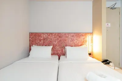 two beds in a room with a red wall at Metz Pratunam in Bangkok