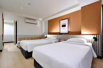 a hotel room with two beds and a mirror at Anya Nana at Sukhumvit Bangkok in Bangkok