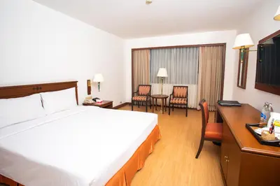 a hotel room with a bed and a desk and chairs at Ramada by Wyndham D MA Bangkok in Bangkok