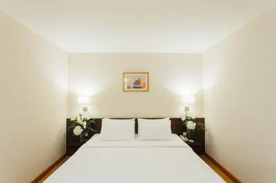 a bedroom with a large white bed with two pillows at Seasons Siam Hotel in Bangkok