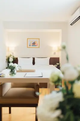 a bedroom with a bed and a desk with flowers at Seasons Siam Hotel in Bangkok
