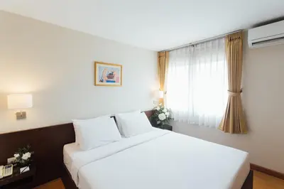 a bedroom with a white bed and a window at Seasons Siam Hotel in Bangkok