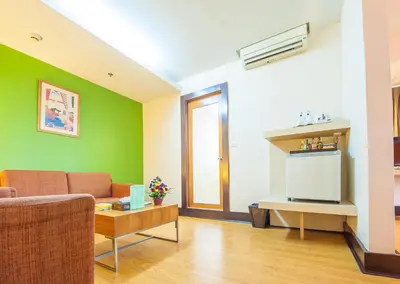 a living room with a couch and a tv at The Seasons Bangkok Huamark in Bangkok