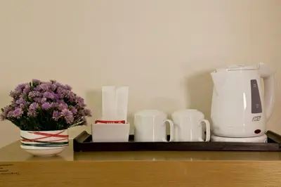 a shelf with a coffee maker and a vase with purple flowers at The Seasons Bangkok Huamark in Bangkok