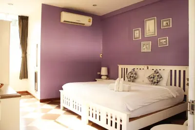 a bedroom with purple walls and a white bed at Feung Nakorn Balcony Rooms and Cafe in Bangkok