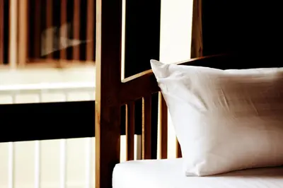 a pillow sitting on a bed next to a chair at Feung Nakorn Balcony Rooms and Cafe in Bangkok