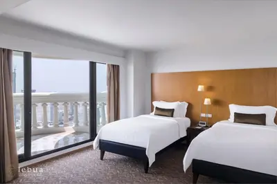 a hotel room with two beds and a balcony at lebua at State Tower in Bangkok