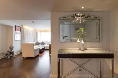 a living room with a mirror and a vase with a plant at Night Hotel Bangkok - Sukhumvit 15 in Bangkok