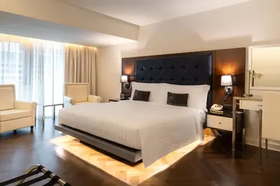 a bedroom with a large white bed and a chair at Night Hotel Bangkok - Sukhumvit 15 in Bangkok