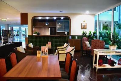 a restaurant with a wooden table and chairs at Ambassador Hotel Bangkok in Bangkok