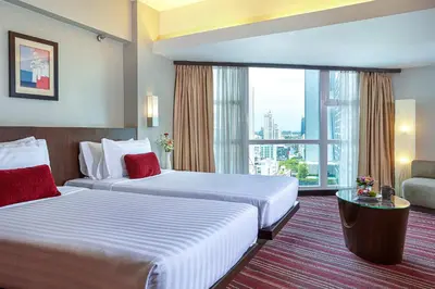 a hotel room with two beds and a large window at Ambassador Hotel Bangkok in Bangkok