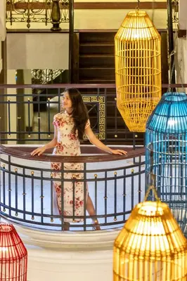 a woman in a dress standing on a balcony at Shanghai Mansion Bangkok in Bangkok