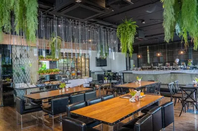 a restaurant with wooden tables and chairs and a bar at Forum Park Hotel in Bangkok