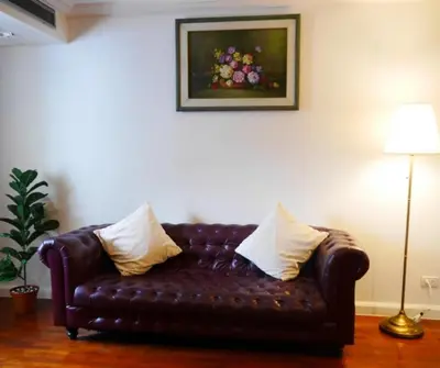a brown leather couch with pillows in a living room at Forum Park Hotel in Bangkok
