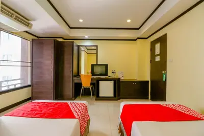 two beds in a room with a desk and a television at Hotel Win Long in Bangkok