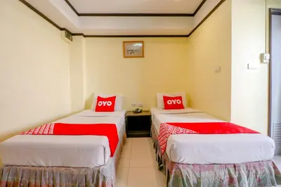 two beds in a room with red and white sheets at Hotel Win Long in Bangkok