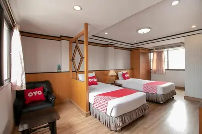 a hotel room with two beds and a chair at Hotel Win Long in Bangkok