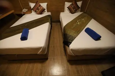 two beds in a room with blue napkins on them at Thai Cozy House in Bangkok