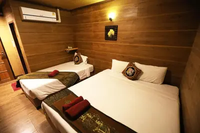 two beds in a room with wooden walls at Thai Cozy House in Bangkok