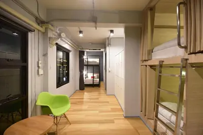 a hallway with a green chair and a table at The Chatbox Silom Hostel in Bangkok