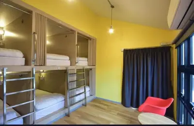 a room with three bunk beds with a red chair at The Chatbox Silom Hostel in Bangkok