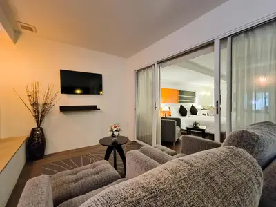 a living room with a couch and a tv at The Key Bangkok Hotel in Bangkok