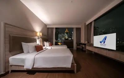 a hotel room with two beds and a flat screen tv at Adelphi Suites Bangkok in Bangkok