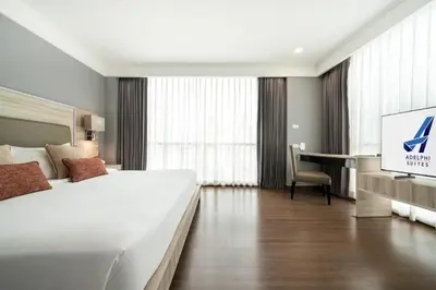 a hotel room with a large bed and a desk at Adelphi Suites Bangkok in Bangkok