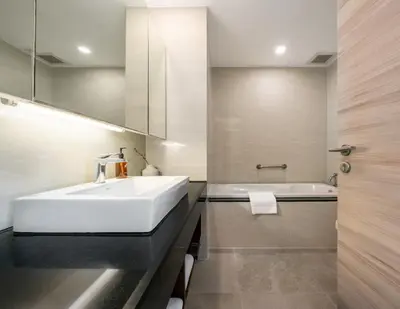 a bathroom with a white sink and a tub at Adelphi Suites Bangkok in Bangkok