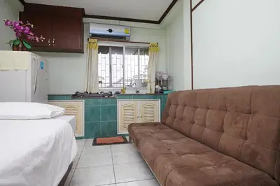 a living room with a couch in front of a kitchen at Amarin Inn in Bangkok