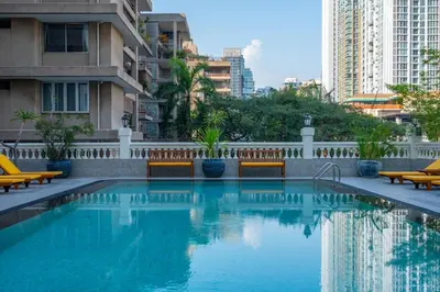a swimming pool with benches and buildings at NH Bangkok Sukhumvit Boulevard in Bangkok