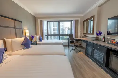 a hotel room with two beds and a television at NH Bangkok Sukhumvit Boulevard in Bangkok