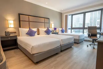 a hotel room with two beds with blue pillows at NH Bangkok Sukhumvit Boulevard in Bangkok