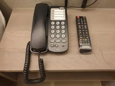 a telephone and a remote control sitting on a table at Studio Ekamai in Bangkok
