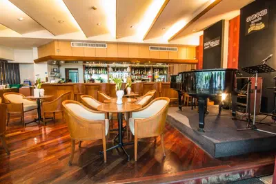 a restaurant with a piano and a table and chairs at Tai Pan Hotel in Bangkok