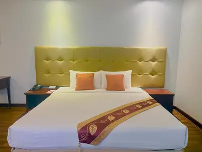 a bedroom with a large bed with a yellow headboard at Tai Pan Hotel in Bangkok