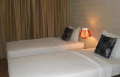 two beds in a hotel room with a lamp at The Blooms Residence in Bangkok