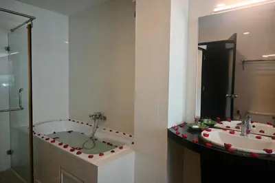 a bathroom with two sinks and a tub with a mirror at Boss Suites Nana Hotel in Bangkok