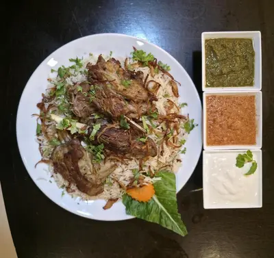 a plate of food with meat and rice on a table at Boss Suites Nana Hotel in Bangkok