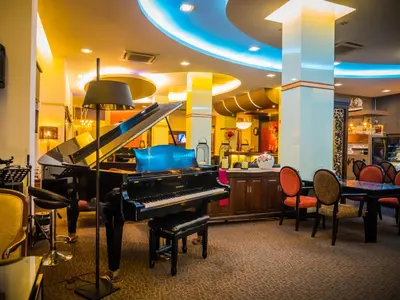a living room with a piano and chairs at Atrium Boutique Hotel in Bangkok