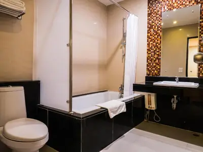 a bathroom with a tub and a toilet and a sink at Atrium Boutique Hotel in Bangkok