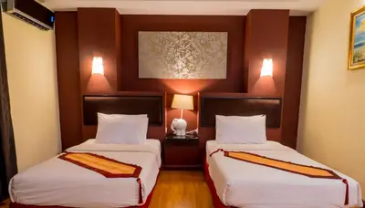 a hotel room with two beds and a painting on the wall at Atrium Boutique Hotel in Bangkok