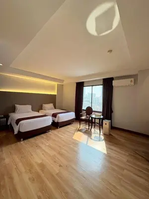 a hotel room with two beds and a table at Atrium Boutique Hotel in Bangkok