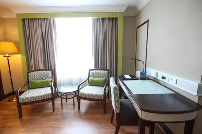 a hotel room with two chairs and a table in a room at Golden Tulip Sovereign Hotel Bangkok in Bangkok