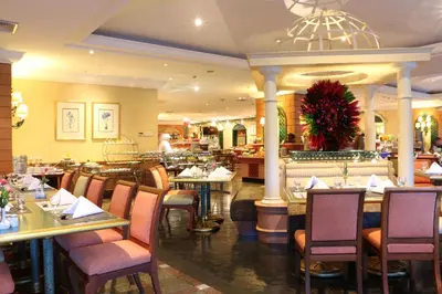 a dining room with tables and chairs in a restaurant at Golden Tulip Sovereign Hotel Bangkok in Bangkok