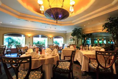 a dining room with tables and chairs and a chandelier at Golden Tulip Sovereign Hotel Bangkok in Bangkok