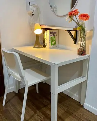 a white desk with a lamp and a vase of flowers at Click Hostel in Bangkok