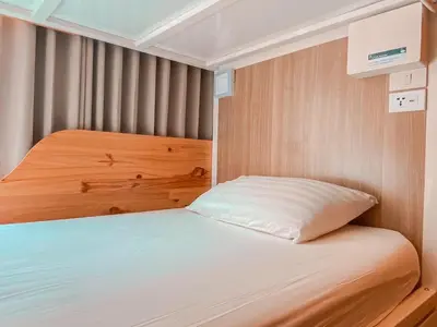 a small bedroom with a bed with white sheets at Click Hostel in Bangkok