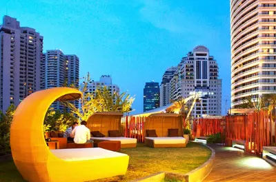 a rooftop patio with couches and chairs in a city at Le Fenix Sukhumvit 11 Bangkok in Bangkok